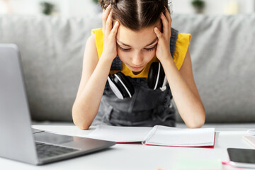 Poster - School Stress Concept. Portrait of tired upset student girl grabbing head sitting at desk, doing homework, reading test, teen studying remotely at home, selective focus. Home Based Learning