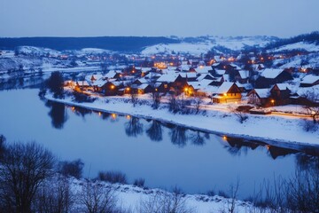 Sticker - Snowy village by the river at dusk with warm lights illuminating cozy homes