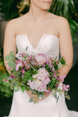 Elegant bride holds a vibrant bouquet of flowers in a lush garden setting