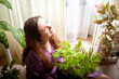 © keleny - A woman enjoys time surrounded by lush indoor plants in a bright and sunny living room
