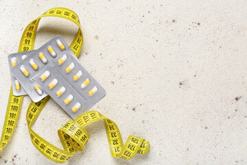 Wall Mural - Blister packs with weight loss pills and measuring tape on beige grunge background