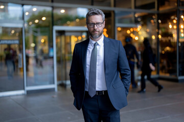 Wall Mural - Successful mature businessman man in business suit standing outdoor on the way to working office