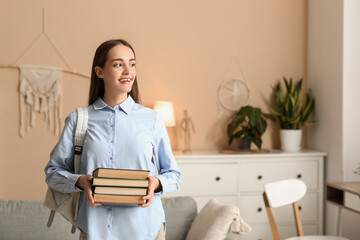 Wall Mural - Beautiful happy female student with stack of books and backpack at home