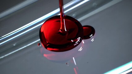 Poster - A slow-motion shot of blood droplets merging on a transparent slide, magnified to reveal cellular details under a clinical white light.
