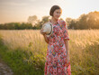 © YURII Seleznov - Young woman walking through picturesque European field in late summer. Golden sunlight, lush greenery, and serene rural atmosphere create peaceful countryside scene.