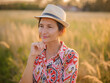 © YURII Seleznov - Young woman walking through picturesque European field in late summer. Golden sunlight, lush greenery, and serene rural atmosphere create peaceful countryside scene.