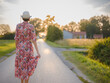 © YURII Seleznov - Young woman walking through picturesque European field in late summer. Golden sunlight, lush greenery, and serene rural atmosphere create peaceful countryside scene.