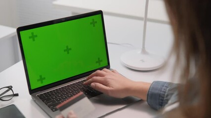 Poster - A focused woman is diligently typing on her laptop, which features a vibrant green screen, all while situated in a stylish, contemporary workspace that reflects a modern business environment