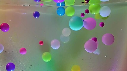 Wall Mural - Create a mesmerizing video of water and oil mixing over a vibrant, gradient background, with colorful balls, circles, and ovals slowly floating and interacting. 
