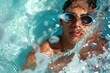 © nsit0108 - Young male swimmer wearing goggles emerging from turquoise water in a swimming pool, creating splashes and enjoying summer activity