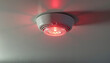 © Ivolga - Smoke detector with red warning light on ceiling.