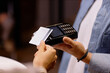 © Seventyfour - Person holding card while conducting transaction with a card scanner device in a retail environment. Close-up capture showing detalles of hands, card, and payment device
