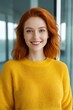 © haiqiang - smiling woman with red hair and bright yellow sweater in office
