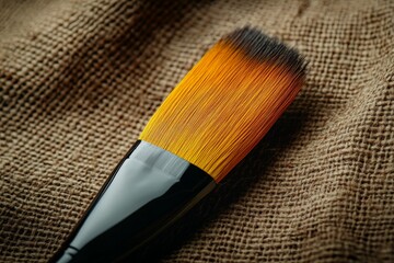 Poster - Brush with vibrant orange and black bristles resting on textured fabric background
