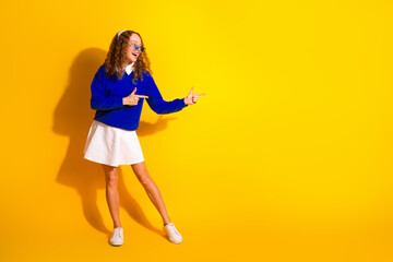 Wall Mural - Energetic young woman gesturing stylishly in a vibrant yellow setting promoting fun and positivity