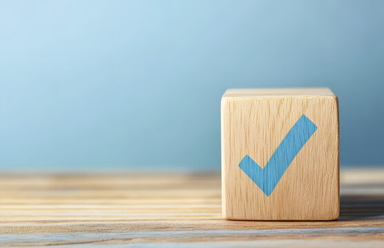 Wooden cube with a blue checkmark on a wooden table, isolated on a pastel background with copy space for text