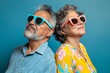 © Markus Schröder - Portrait of a merry latino couple in their 60s wearing a trendy sunglasses over pastel blue background