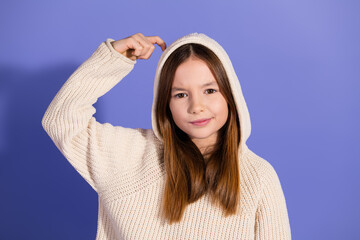 Wall Mural - Lovely young girl in a stylish sweater posing confidently against a purple background