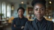 © Raul - Two women in sleek black outfits stand in a stylish workspace, one in focus with a determined expression while the other appears contemplative in the background, suggesting a meaningful dialogue