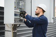 © Serhii - A male electrician works in a switchboard