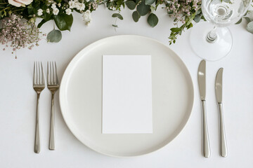 Elegant Place Setting with Menu Card: A pristine white dinner plate, set with gleaming silverware, presents a blank menu card, ready to be personalized for an elegant event.