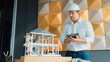 © Summit Art Creations - Professional caucasian architect engineer using tablet analysis house construction and checking model structure carefully with architectural model and equipment placed on meeting table. Manipulator.