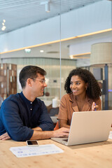 Aufkleber - Two young busy diverse colleagues business people using laptop in modern office. Happy team employees working on computer discussing online technology data solutions at work. Vertical photo.