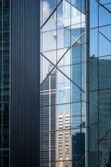 Aufkleber - A close-up view of modern office building glass facades reflecting the surrounding city, showcasing an abstract and geometrical perspective of contemporary architecture.