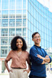 © insta_photos - Vertical portrait of young happy professional corporate office team of two diverse confident female and male partners business people man and woman standing outdoors on city street looking at camera.