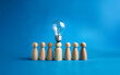 © YiuCheung - A single light bulb stands atop a wooden figure, representing a brilliant idea among a group of figures.