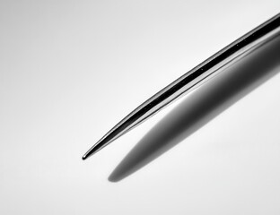 Aufkleber - Close-up of a sleek, metallic, pointed object casting a shadow on a bright surface.
