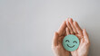 © SewcreamStudio - Hands holding smile emoji face, positive mental health, world mental health day concept.