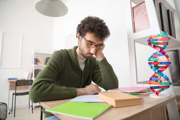 Wall Mural - Tired male student studying at table in library