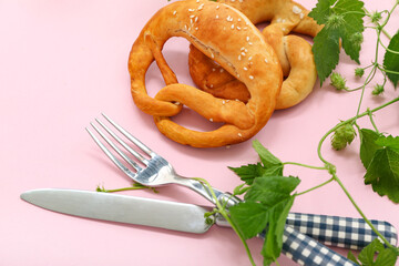 Wall Mural - Soft pretzels with cutlery on pink background