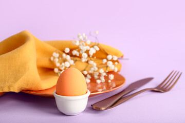 Wall Mural - Beautiful festive table setting for Easter with egg and flowers on lilac background