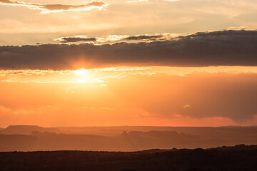 Wall Mural - the sun is setting over a mountain range, casting a warm glow over the landscape