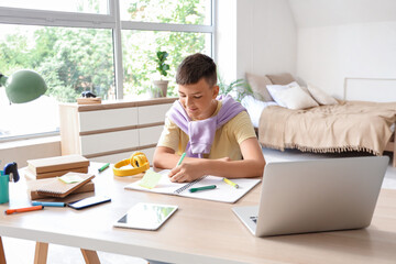 Wall Mural - Teenage boy doing homework at table in bedroom