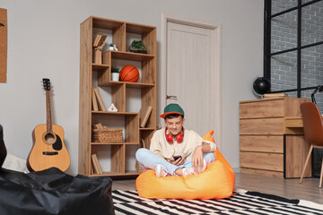 Wall Mural - Teenage boy using mobile phone on beanbag in bedroom