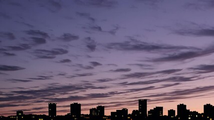 Aufkleber - A dreamy, pastel-toned skyline at twilight, highlighted by the comforting glow of interior lights radiating through distant windows.
