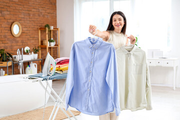 Wall Mural - Beautiful young happy woman with shirts and iron on board in bathroom