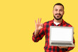 © Pixel-Shot - Young man with blank laptop showing OK on yellow background