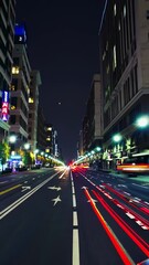 Aufkleber - An urban night scene where glowing red, yellow, and white lines sweep across a dimly lit street, conveying the pulse of bustling city traffic.
