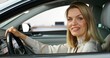 © m-art - A stylish woman smiles looking at the camera sitting in the driver's seat of a car