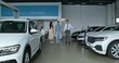 © m-art - The car dealership manager shows cars to customers by taking them through the showroom. A family with a child chooses a car