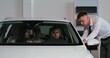 © m-art - A family with a child is sitting in a car in a showroom. The car dealership manager is talking to them, standing nearby