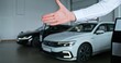 © m-art - The car dealership manager shakes hands with the car buyer while standing in the showroom. Close-up of their hands, unrecognizable persons
