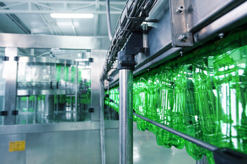 Poster - green plastic bottles moving along a production line in a factory setting during daylight hours