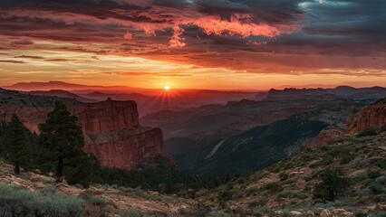 Poster - Stunning sunset over rugged mountains with vibrant orange and purple hues, highlighting dramatic clouds and lush green foreground.