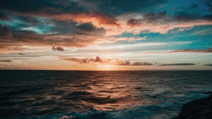 Poster - Vibrant sunset over the ocean with deep blue and orange hues, clouds scattered across the sky, reflecting sunlight on rippling water.