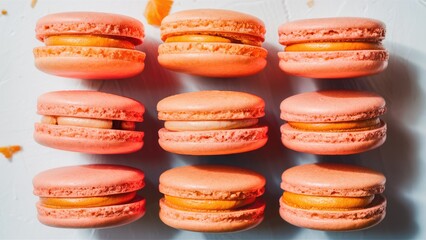 Poster - Pink macarons arranged in two rows on a clean white background, featuring a soft orange filling that creates a visually appealing dessert display.